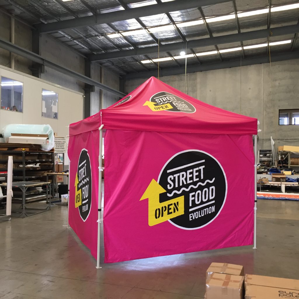 A pink, partially enclosed gazebo with a black logo behind street food evolution in white text